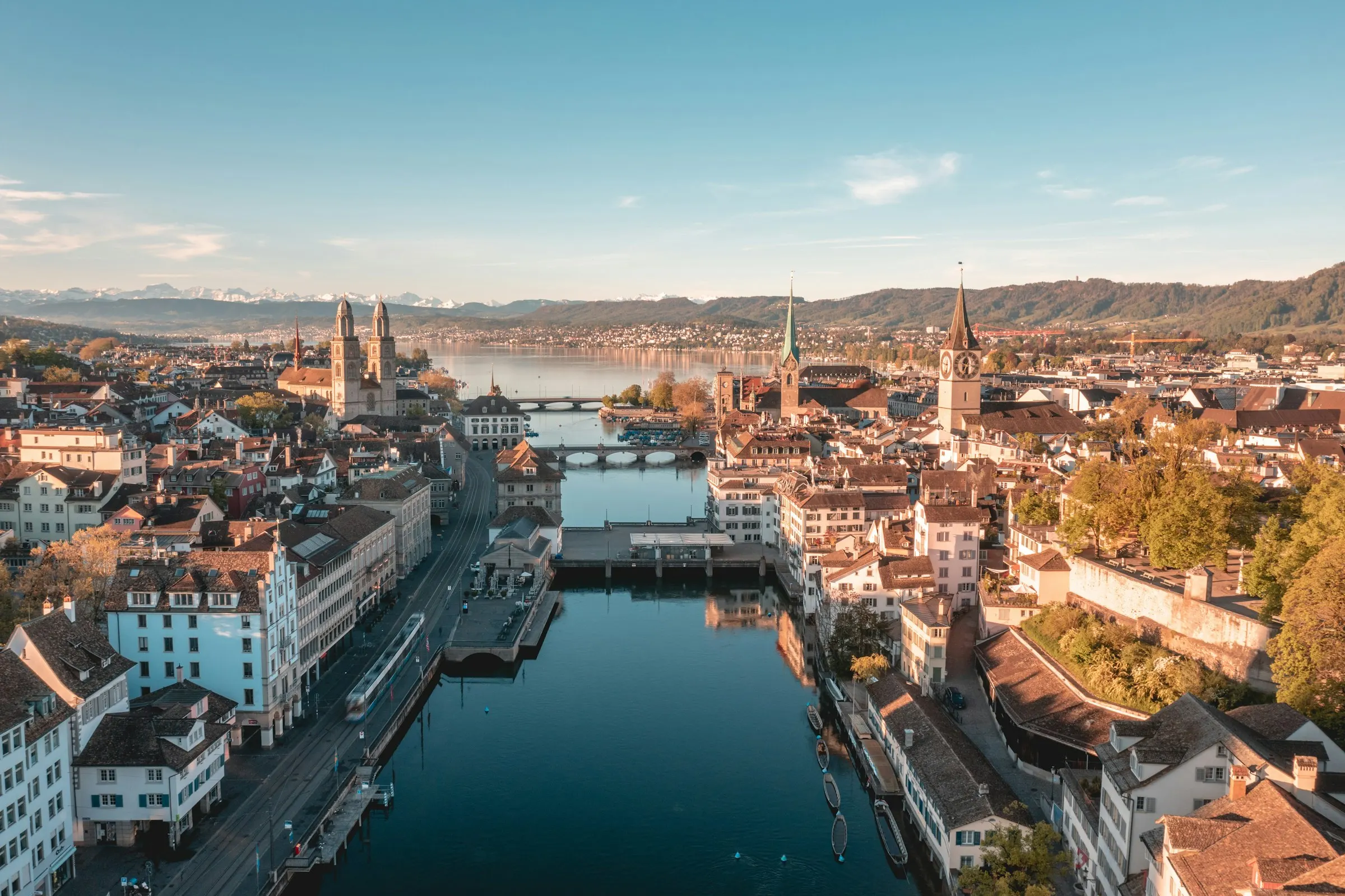 Zürcher Altstadt an der Limmat am Morgen, dahinter der See und die Alpen